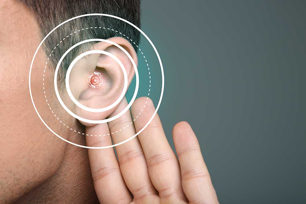 A person holds a hand close to their ear, with concentric circles digitally added over the ear to represent hearing or sound waves.